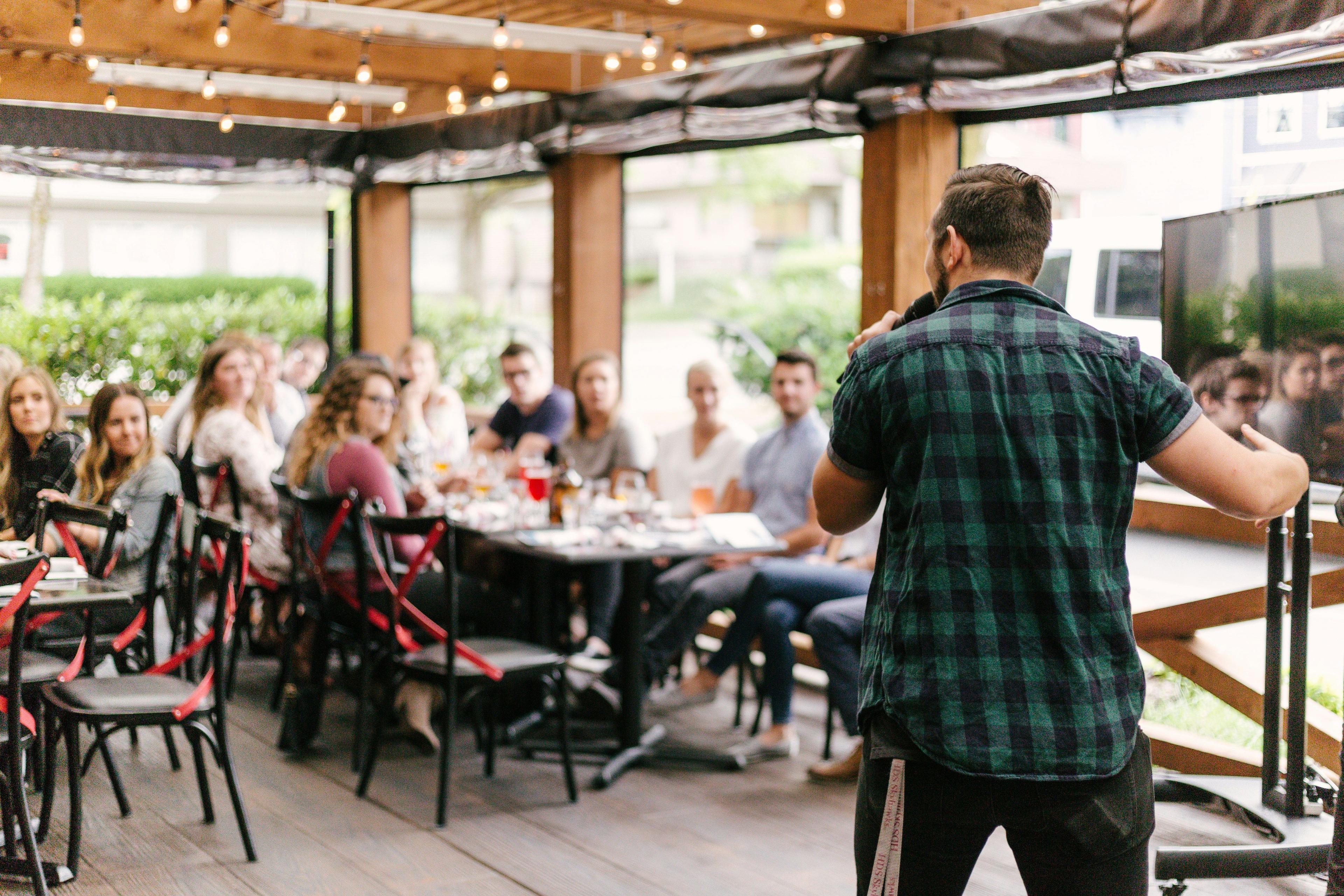 A speaker addressing a group of people at an event, symbolizing video content marketing tactics used to engage live audiences and drive brand awareness.