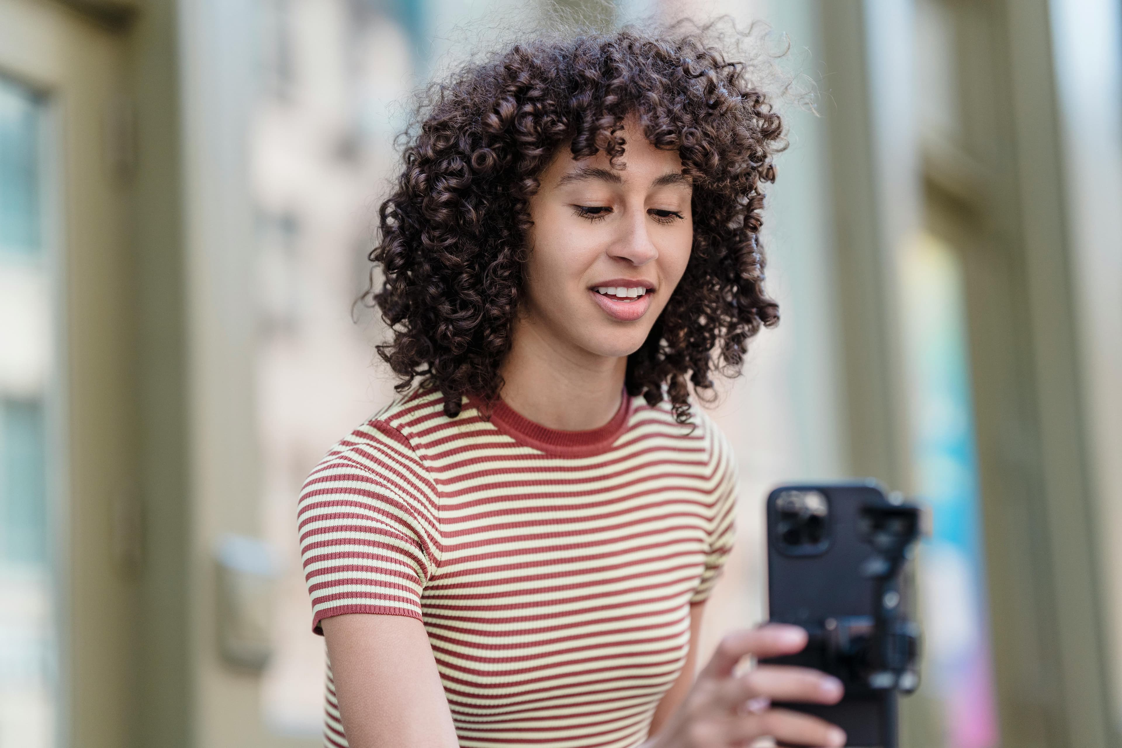 A young woman using her smartphone to create engaging content, sharing insights on how a free AI landing page can simplify website creation and drive audience engagement.