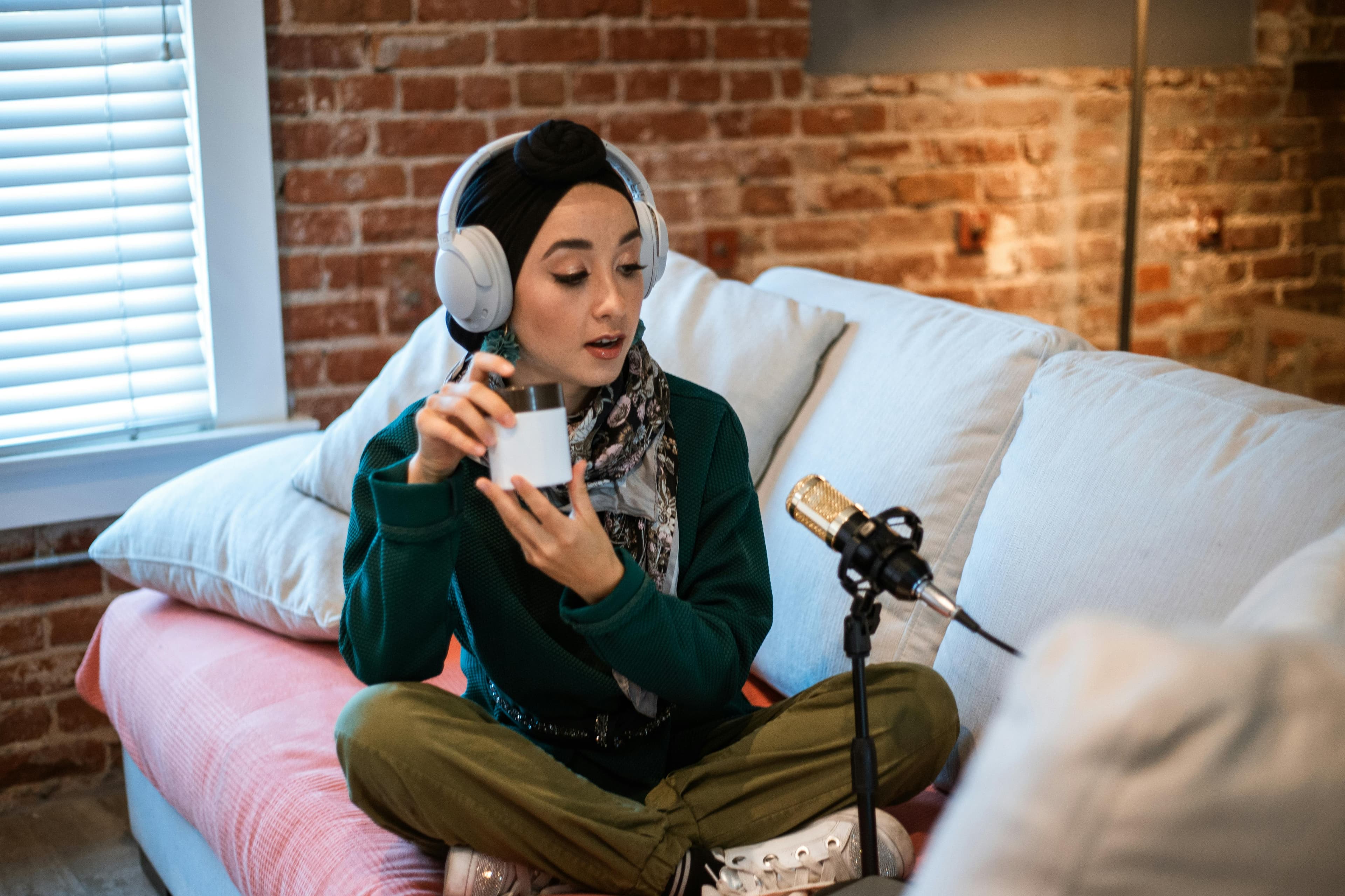 a content creator is recording a podcast or product review using a microphone and headphones while sitting on a couch. This setup is ideal for creating engaging content for top landing pages aimed at boosting audience interaction and conversion rates through dynamic audio or video features.