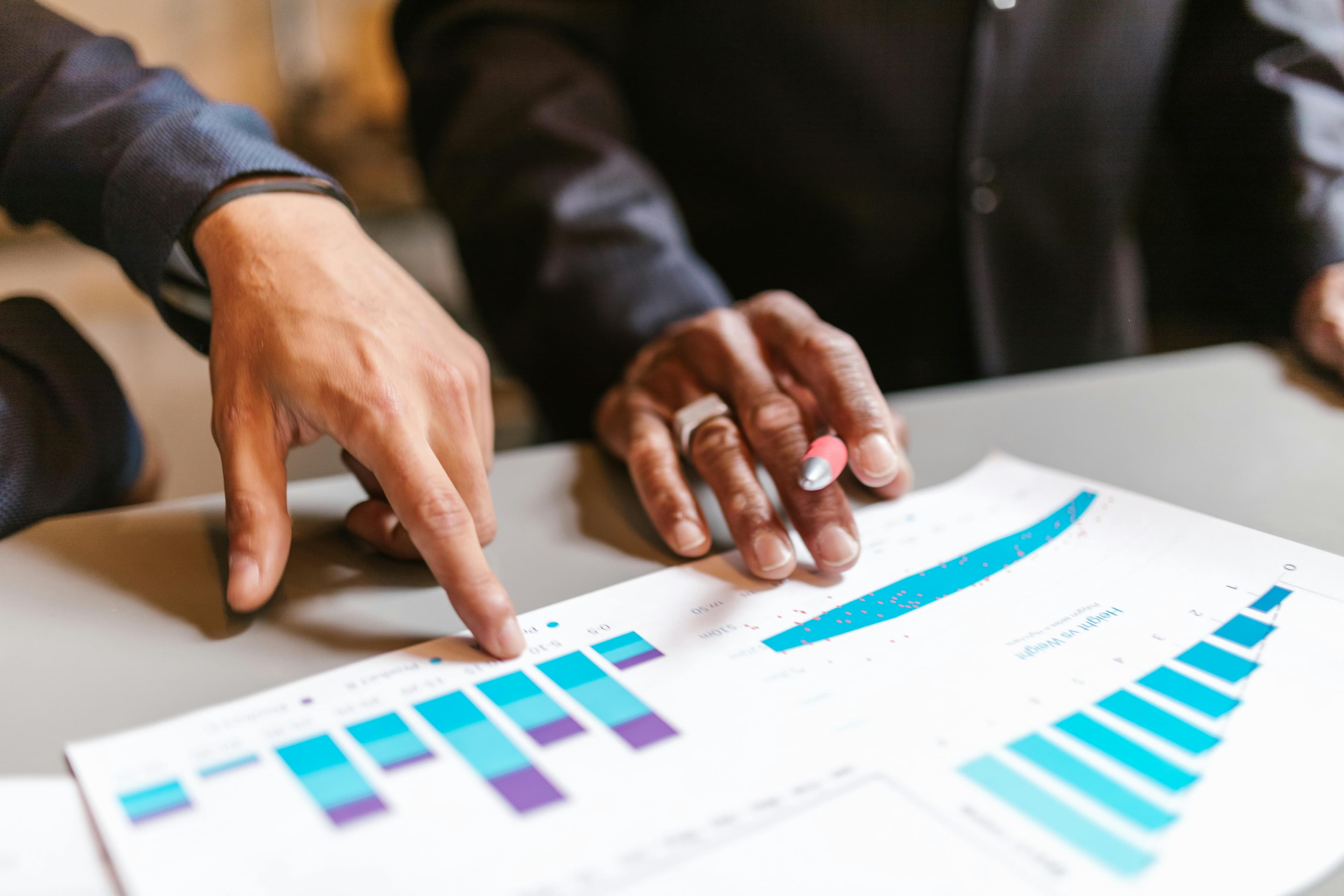 two individuals are examining a chart with colorful bar graphs, likely discussing data trends and making decisions related to conversion rate optimization.