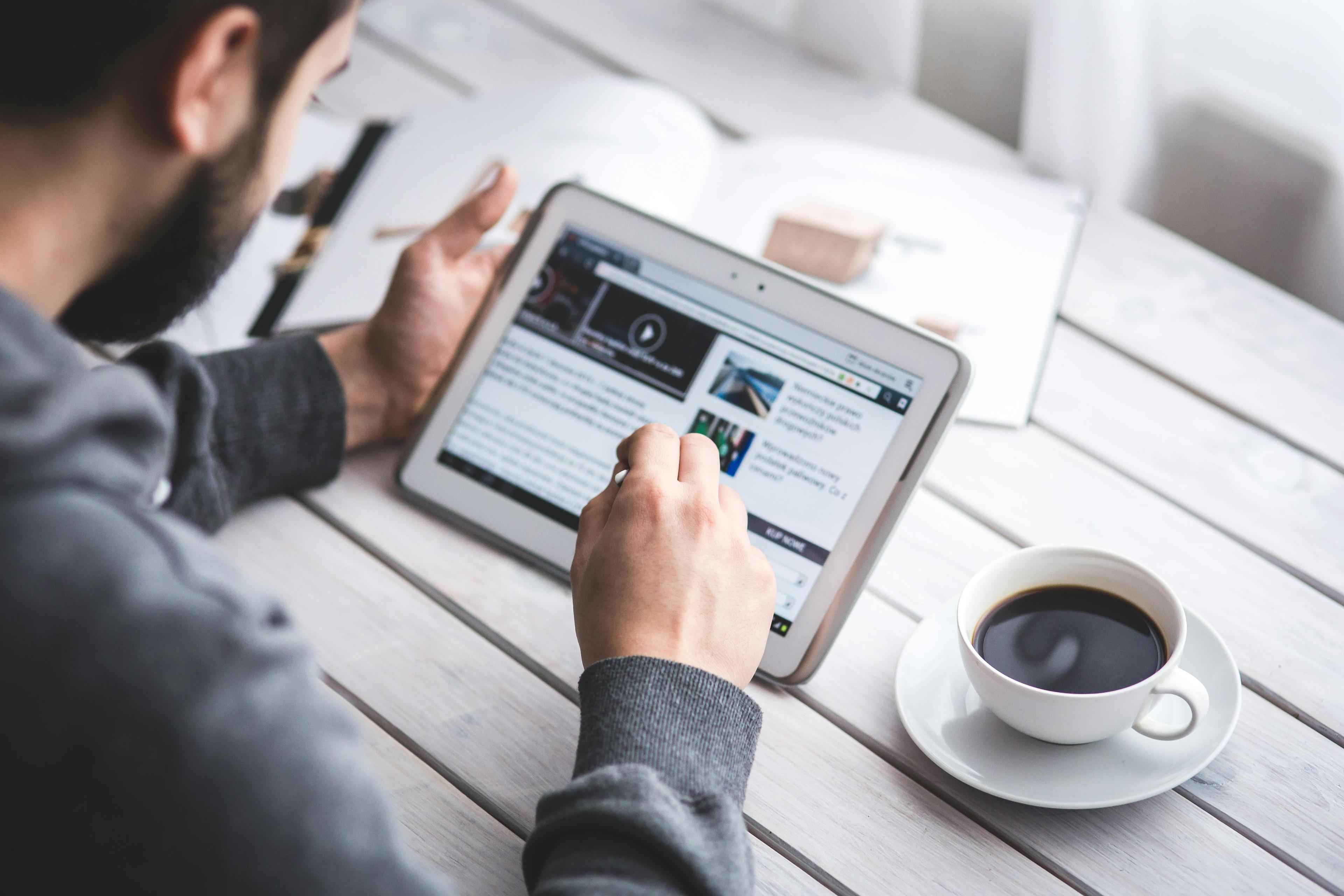 A person reading a website on a tablet, showing how website design for small business should prioritize mobile responsiveness and accessibility for users.