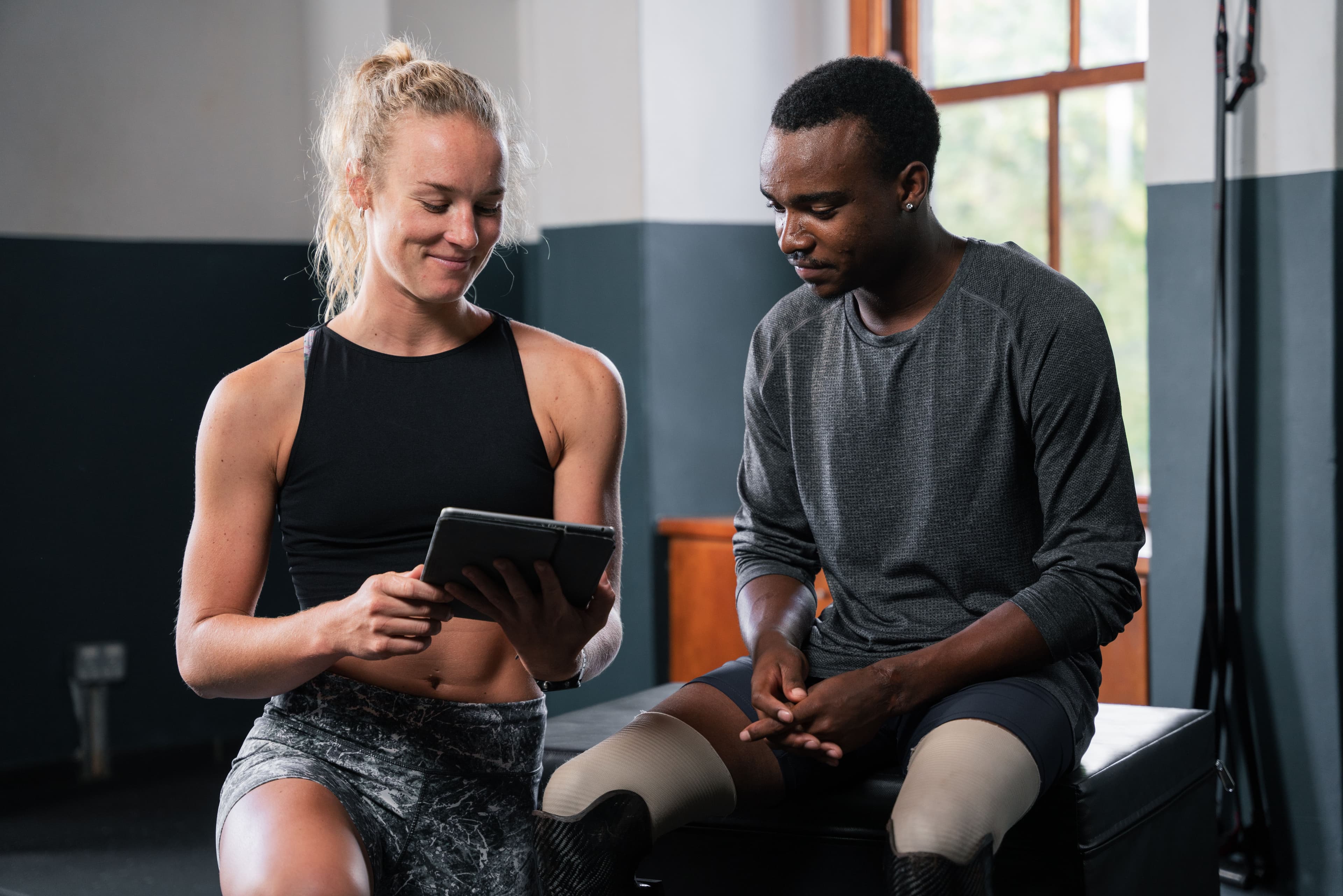 A personal trainer showing a digital tablet to an athlete during a training session in a gym. This image can symbolize personalized customer interactions, much like how email marketing delivers tailored messages to engage specific audiences.