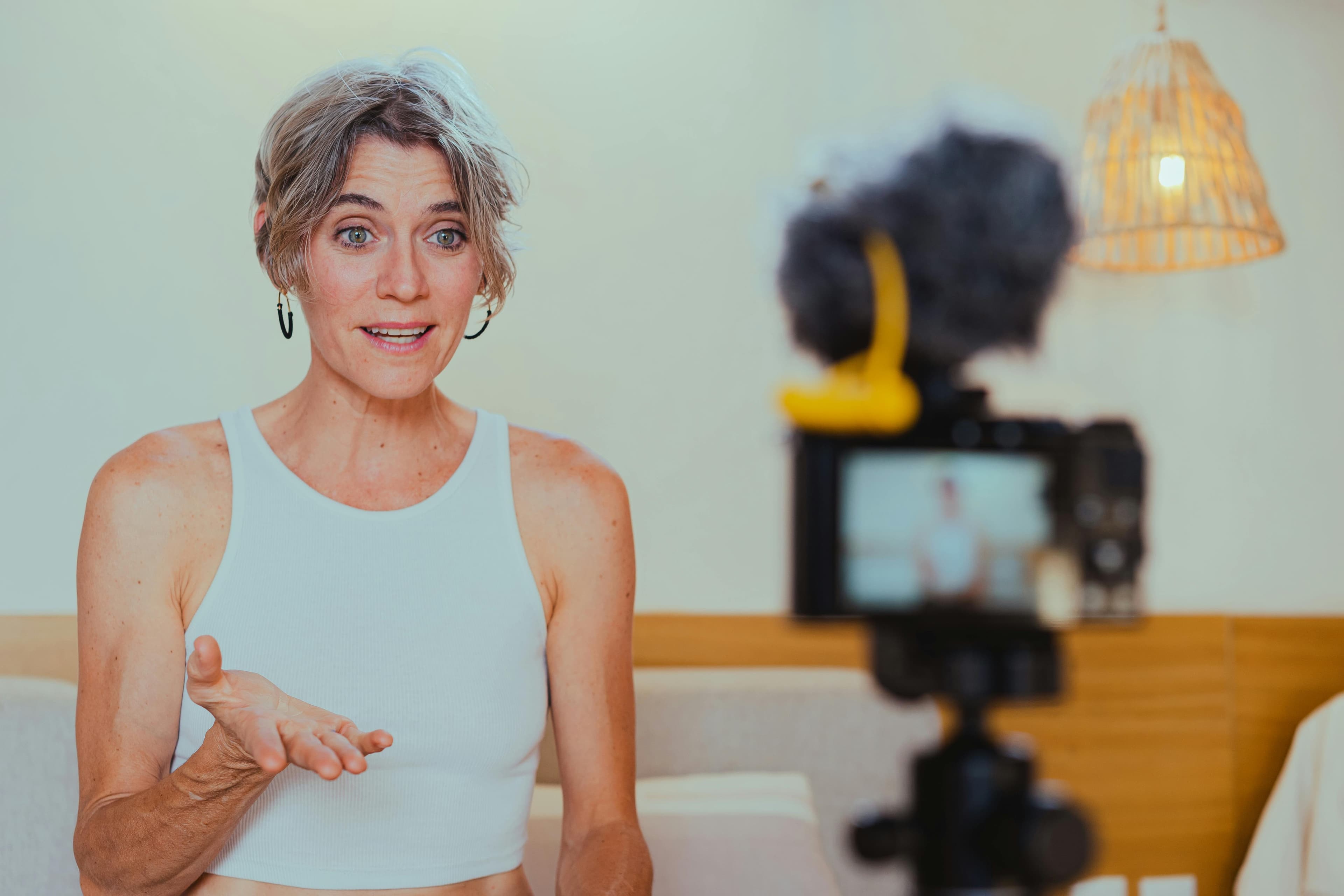 A woman in a casual setting speaking confidently into a camera with a microphone attached. This scene explains "what is conversion in marketing?" by highlighting how personalized video content drives engagement and influences viewers to take action.