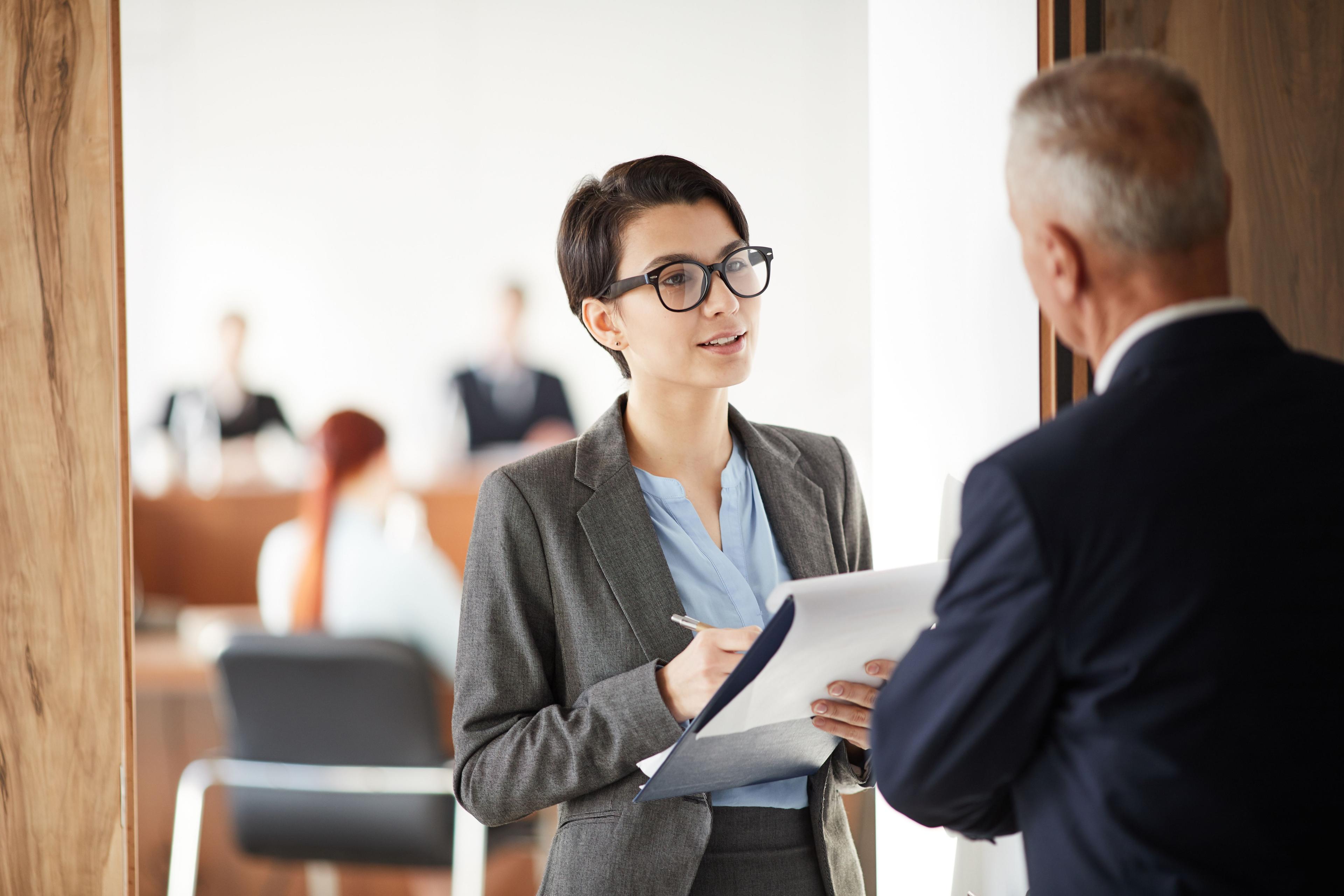 Young professional discussing real estate lead generation with a colleague in an office.