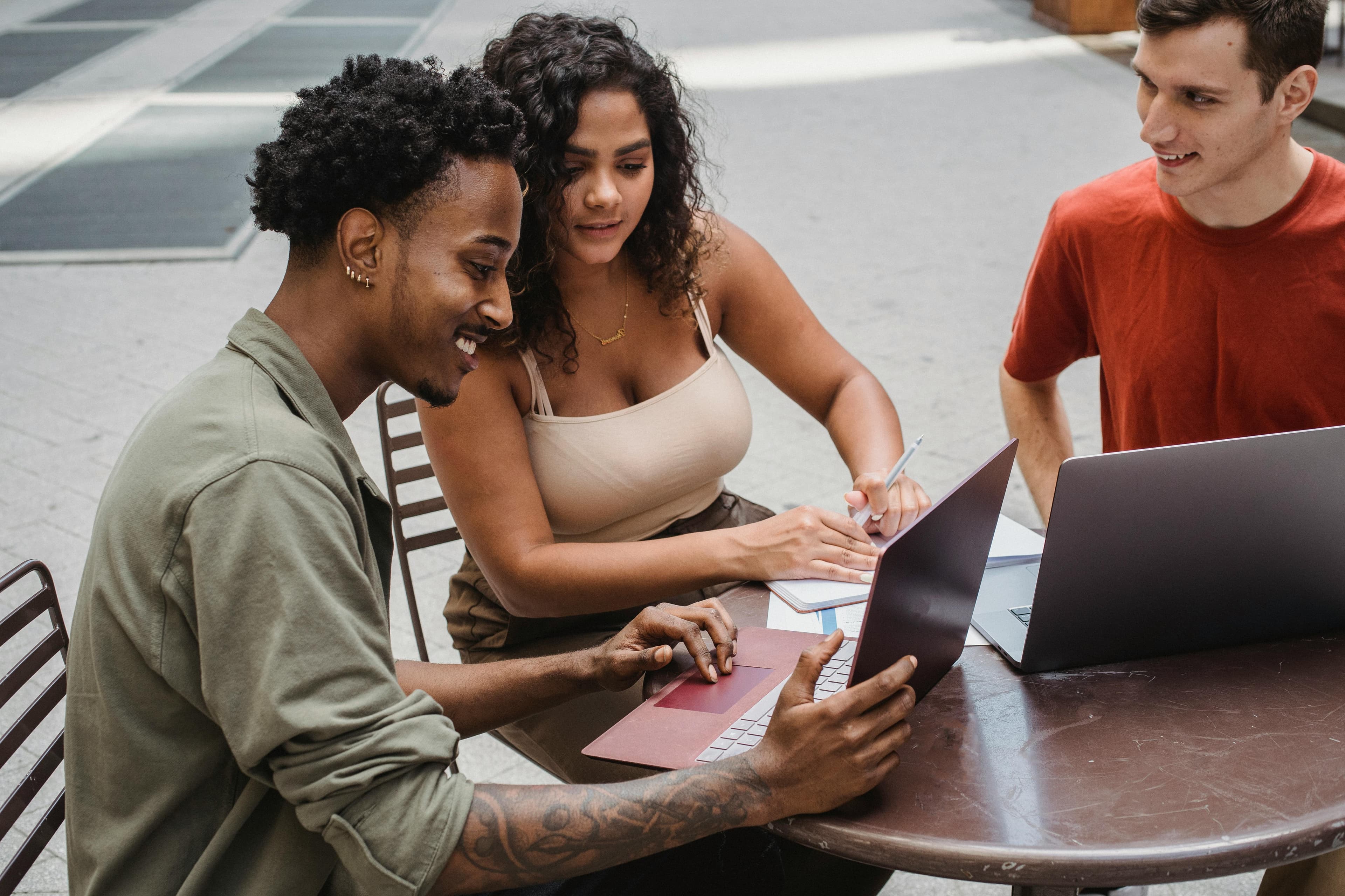 A group of diverse young professionals collaborating with laptops at an outdoor table. This teamwork reflects how email marketing can integrate seamlessly into multi-channel marketing strategies, engaging different segments of an audience.