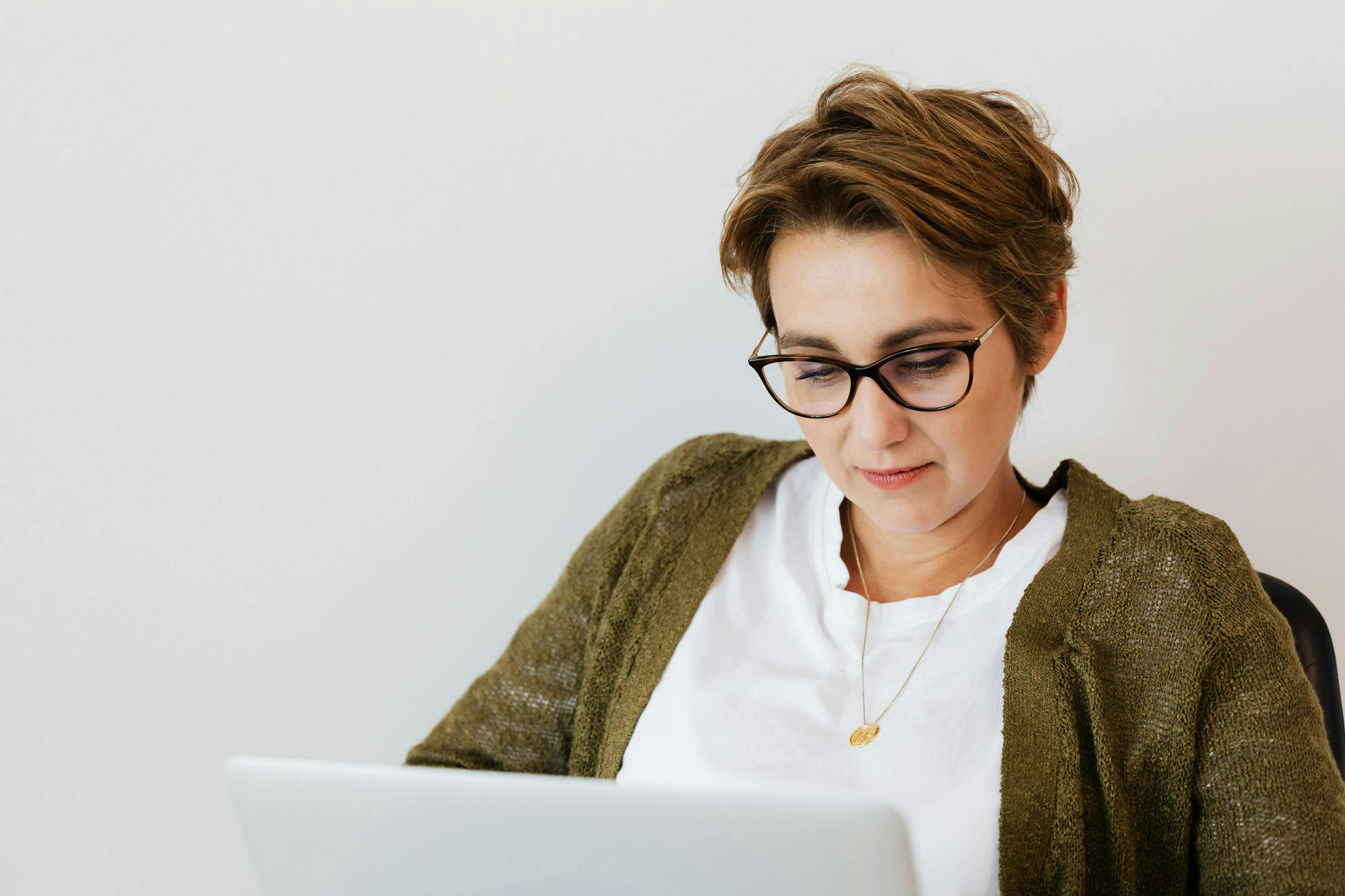 A woman with short hair and glasses working on a laptop, representing digital marketing services for small businesses.