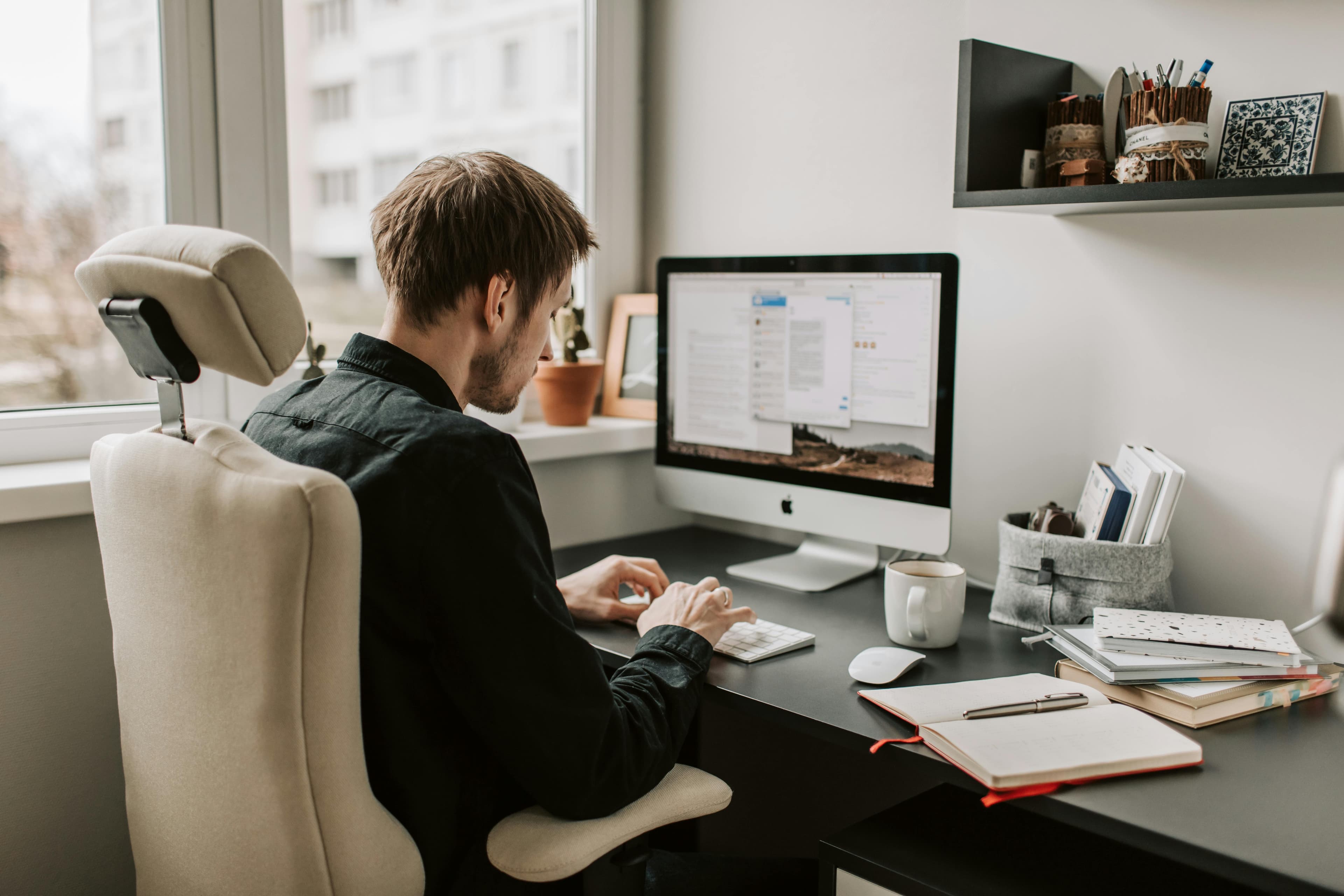 A man working on a desktop computer at home, analyzing data from an A/B testing program to improve user experience.