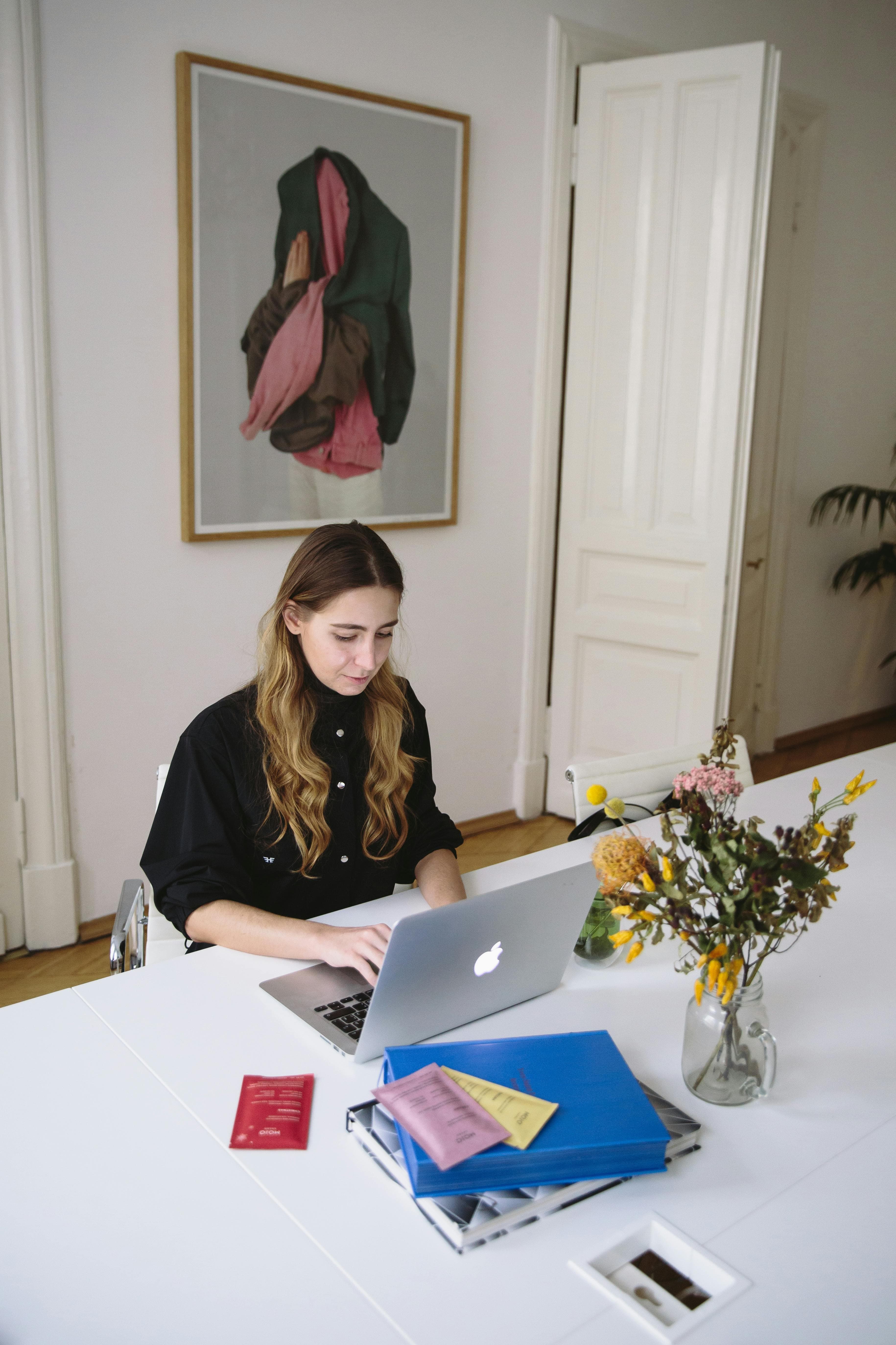 a woman is working on a laptop in a minimalist, professional setting. This could depict a scenario where someone is developing or optimizing top landing pages by focusing on clear, user-friendly designs that drive engagement and lead generation.