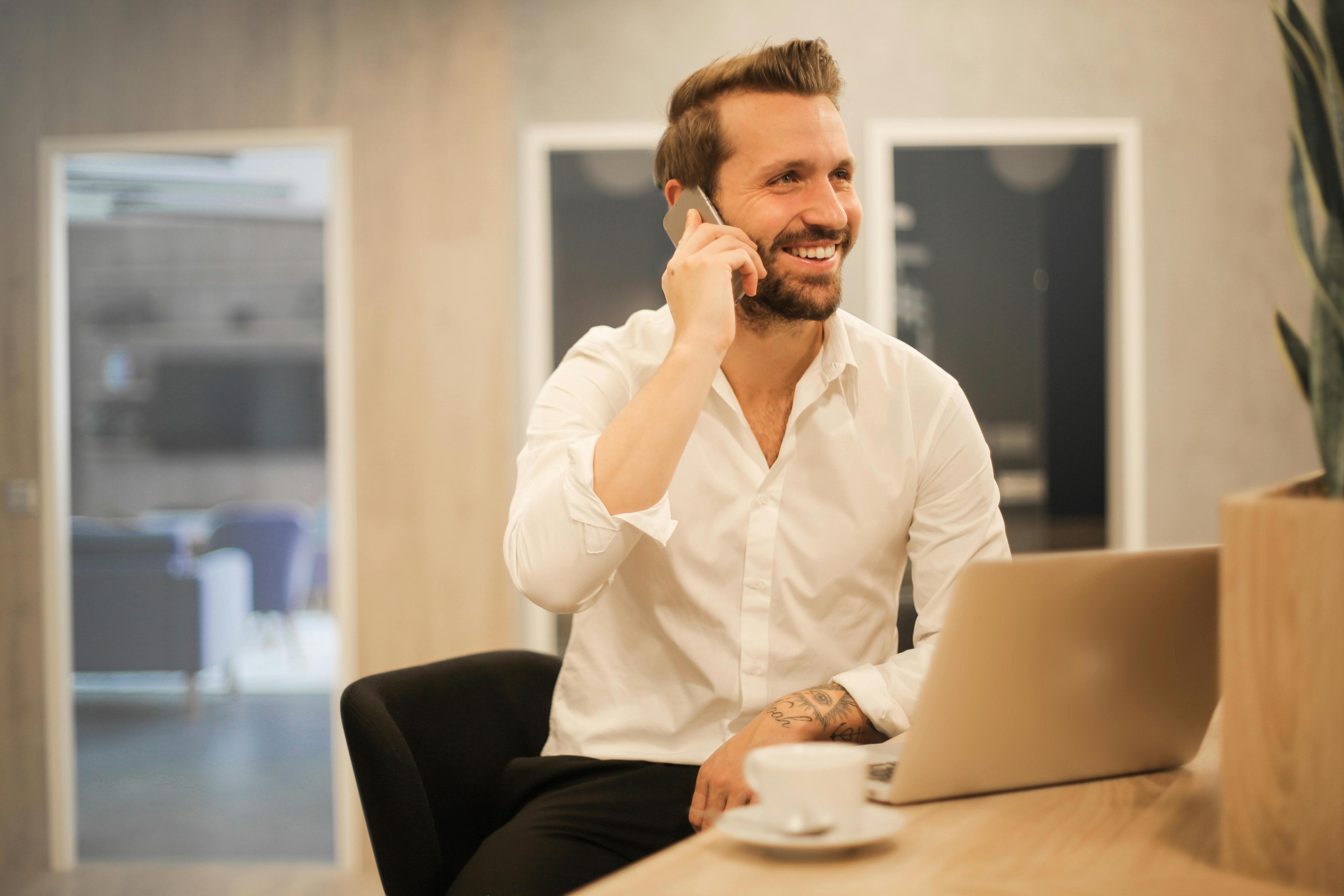 A professional sitting at a desk, on the phone, with a laptop in front of him. His relaxed yet focused demeanor reflects the flexibility and convenience that custom van conversions can provide for mobile entrepreneurs.