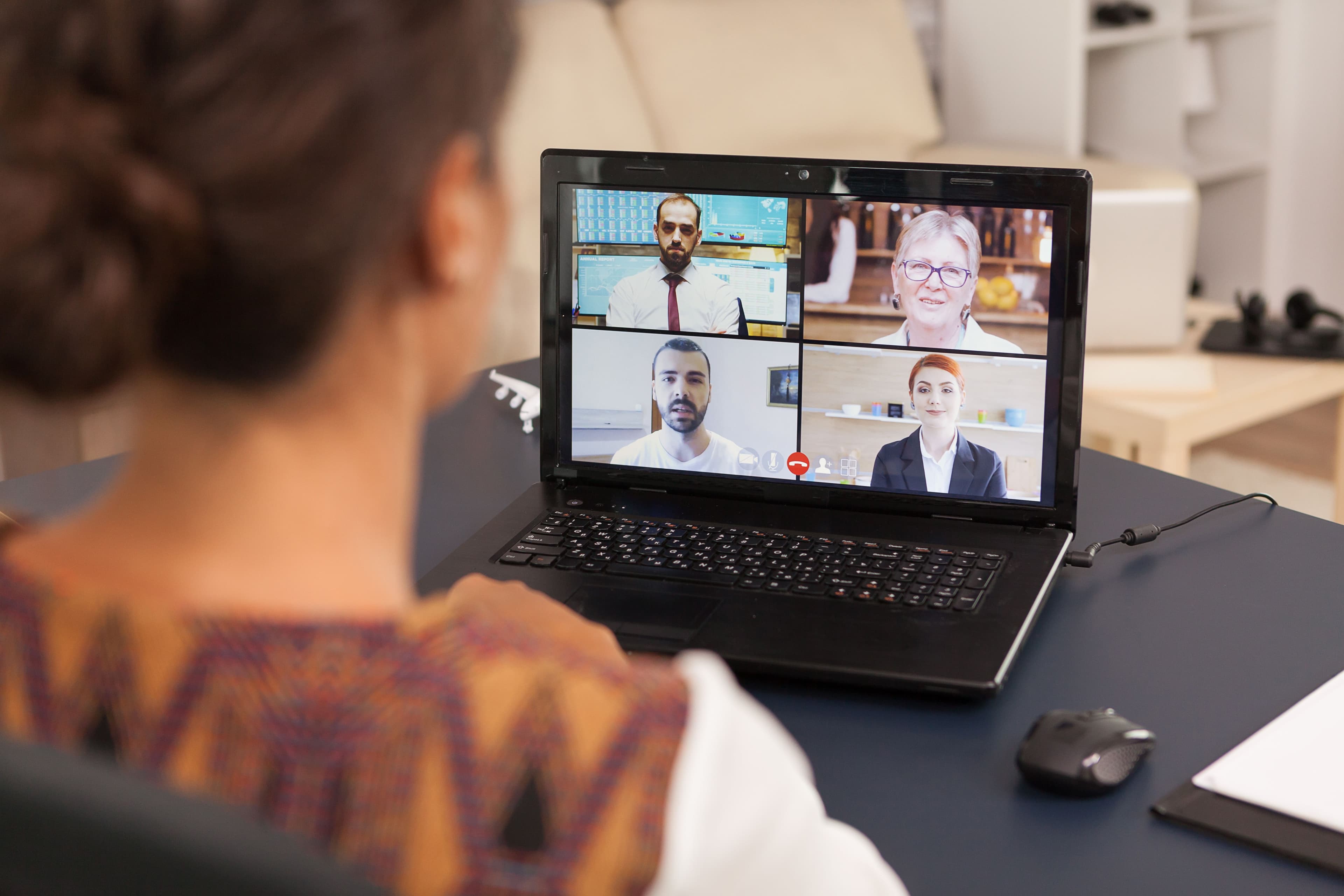 A person participates in a video call on a laptop, engaging in a virtual meeting with four other professionals. This scene captures the dynamic interaction typical of a "small business marketing coach" who conducts virtual training sessions or consultations to connect with clients remotely.