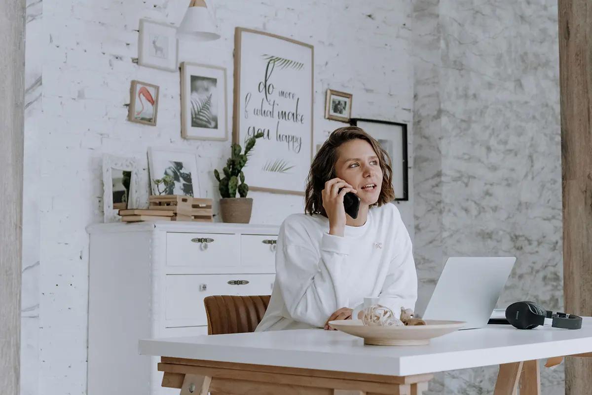 Woman working from home, talking on the phone and using a laptop, illustrating the dynamic environment of a content marketing agency