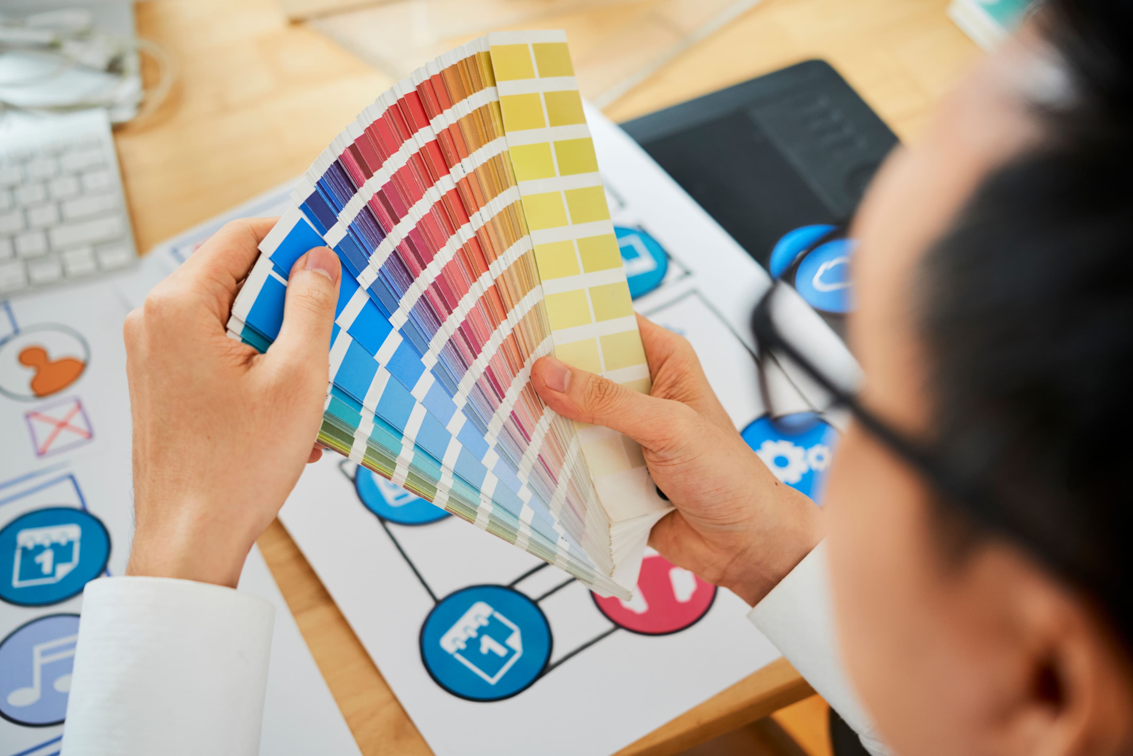 A designer holds a palette of color swatches while working on a new project, focusing on color choices that appeal to a target audience. This image highlights the importance of visual branding in startup marketing to create a strong brand identity.