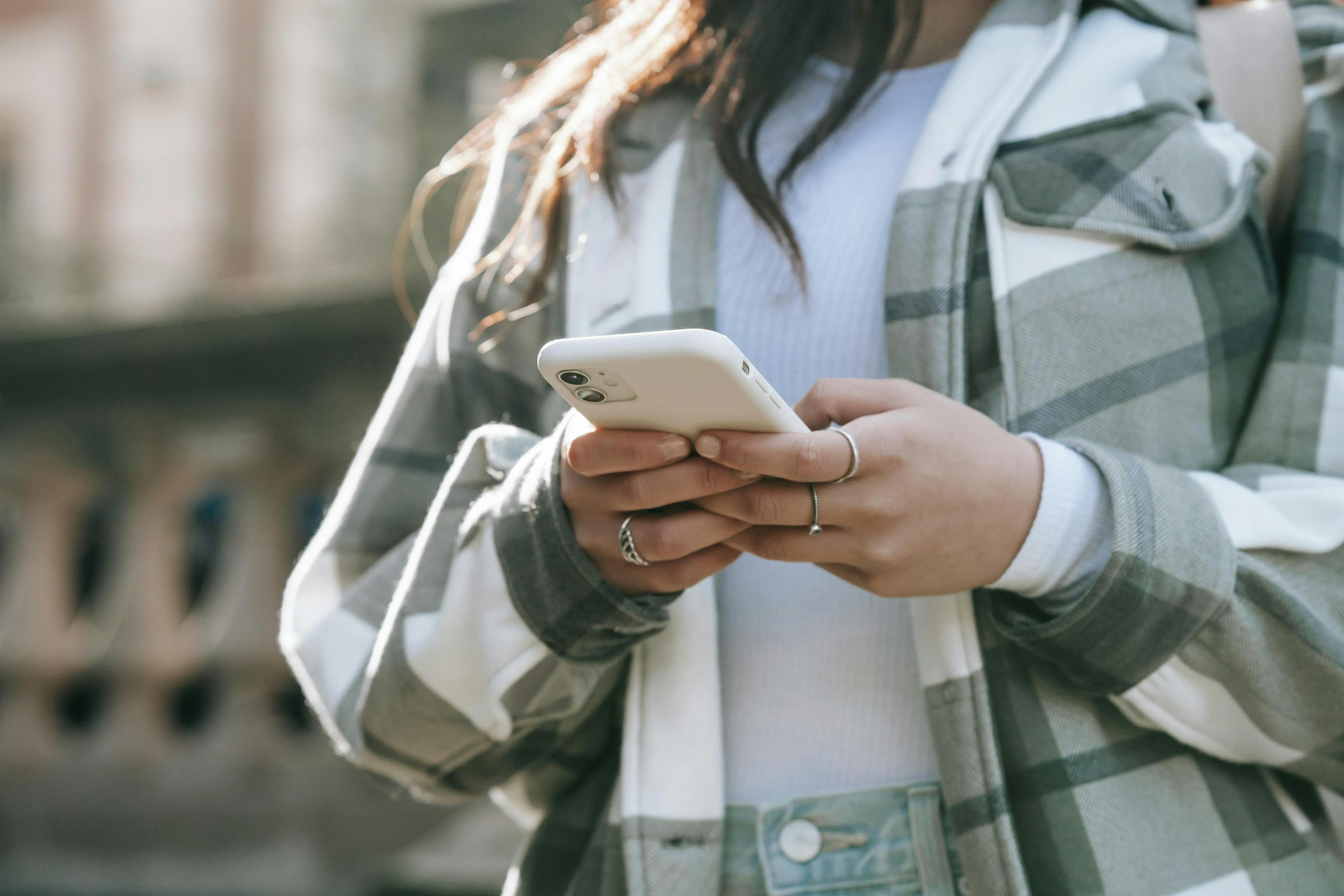 Close-up of a woman using a smartphone while wearing a plaid jacket, representing conversion rate marketing.