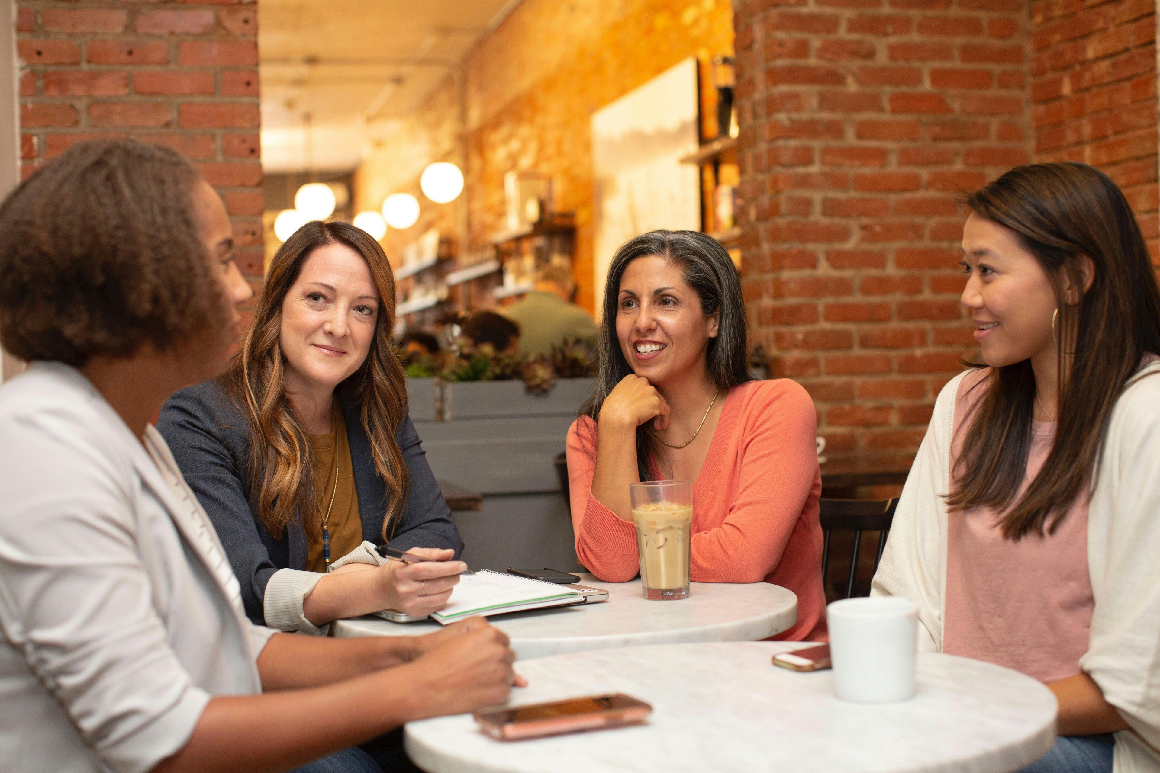 A group of businesswomen engaging in a discussion at a cafe, highlighting the importance of collaborative efforts in website design for small business to create engaging and user-friendly online platforms.